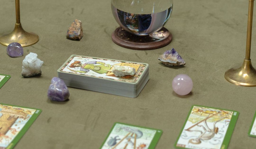 Tarot cards and a crystal ball laid out on a table, representing the psychic reading services that affiliate publishers promote